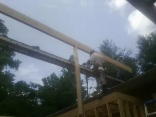 Carpenter setting a ridge beam over a new addition frame — Ice Dam Removal by Roofing Brothers in Ernul