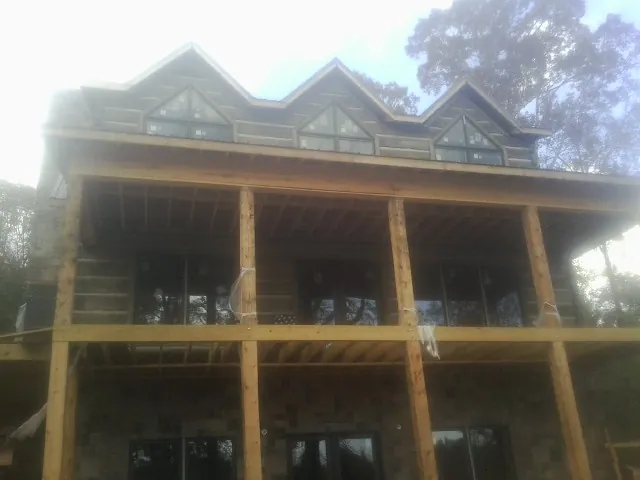Dormers and porch framing on a large log home under construction — Roof Coating work by our crew in Ernul