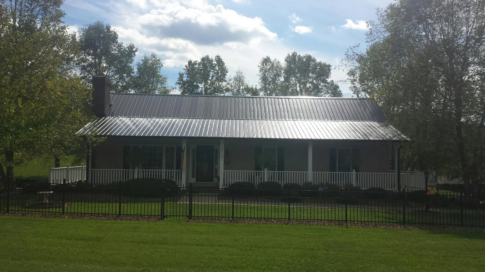 Gray metal roof on a brick ranch with a full width front porch — Gutter Guard Installation work by our crew in Ernul