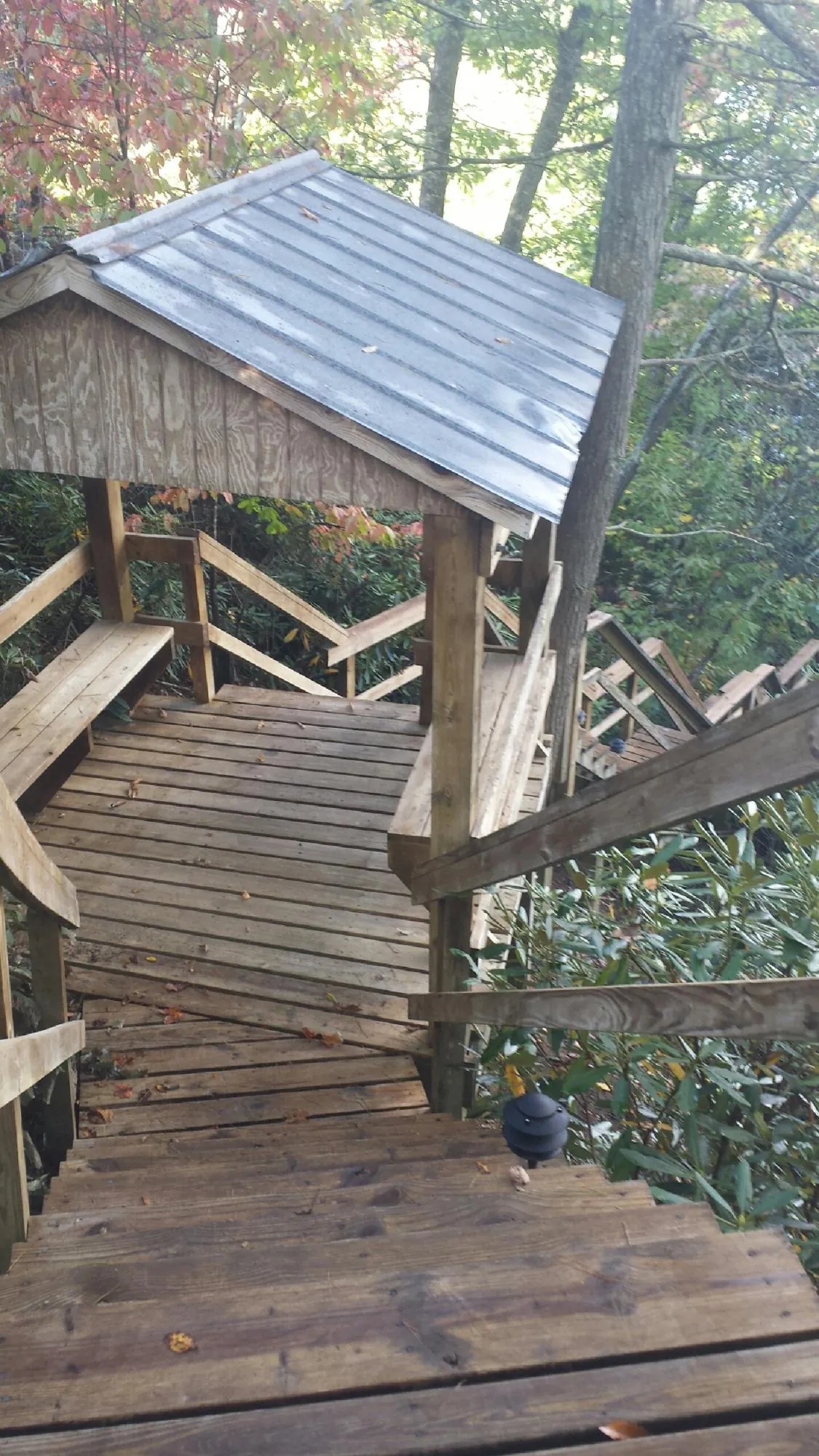 Metal roofed shelter over wooden steps on a wooded walkway — Skylight Repair & Installation work by our crew in Ernul