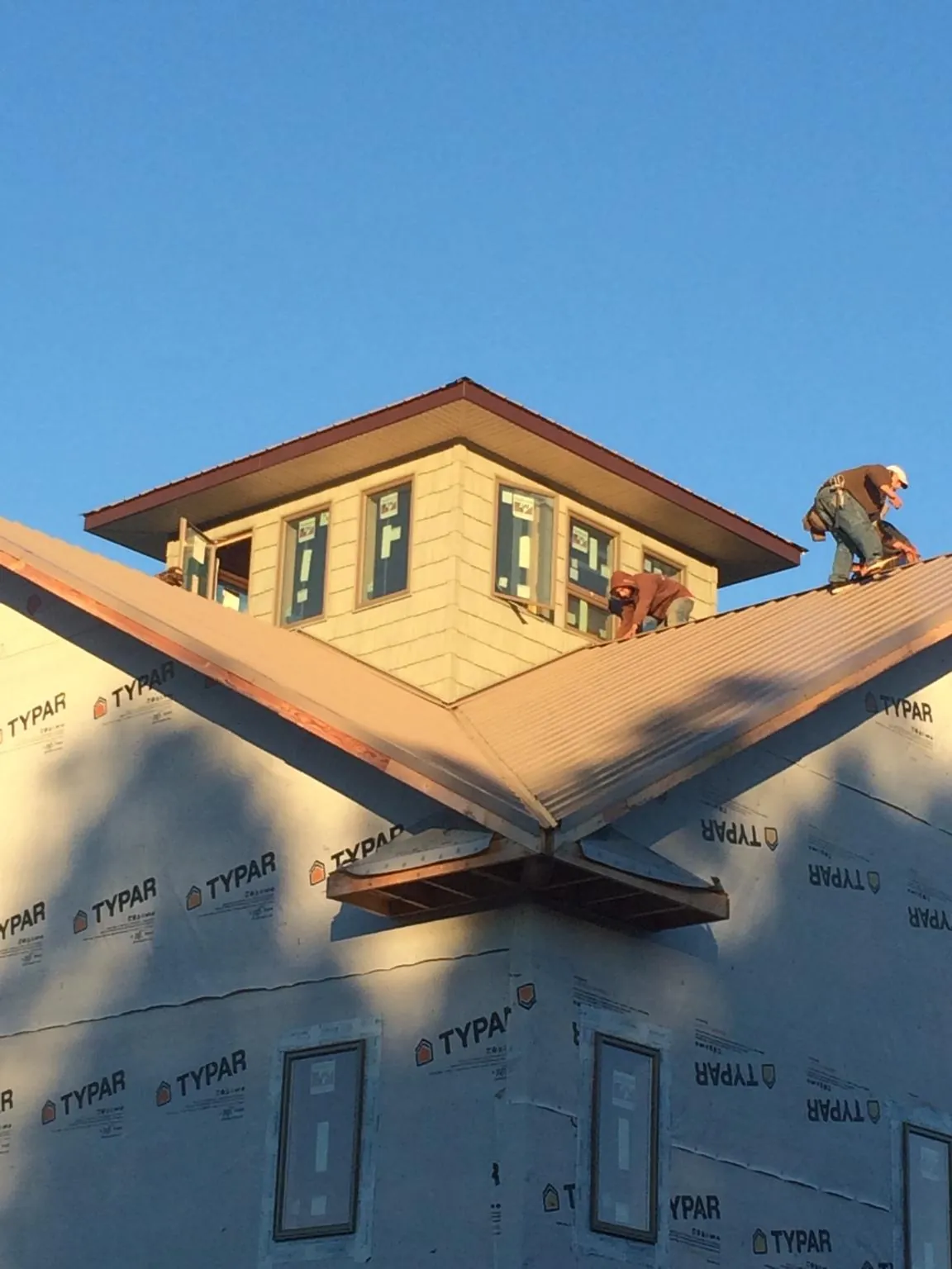 Roofers working around a rooftop cupola on a new metal roof at sunset — Roof Waterproofing in Ernul by Roofing Brothers